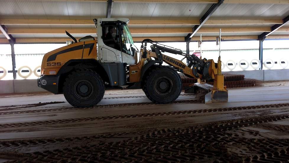 Vrijdag 18 april wordt met een shovel het zand in de stal vlak geschoven voordat het beton wordt gestort.