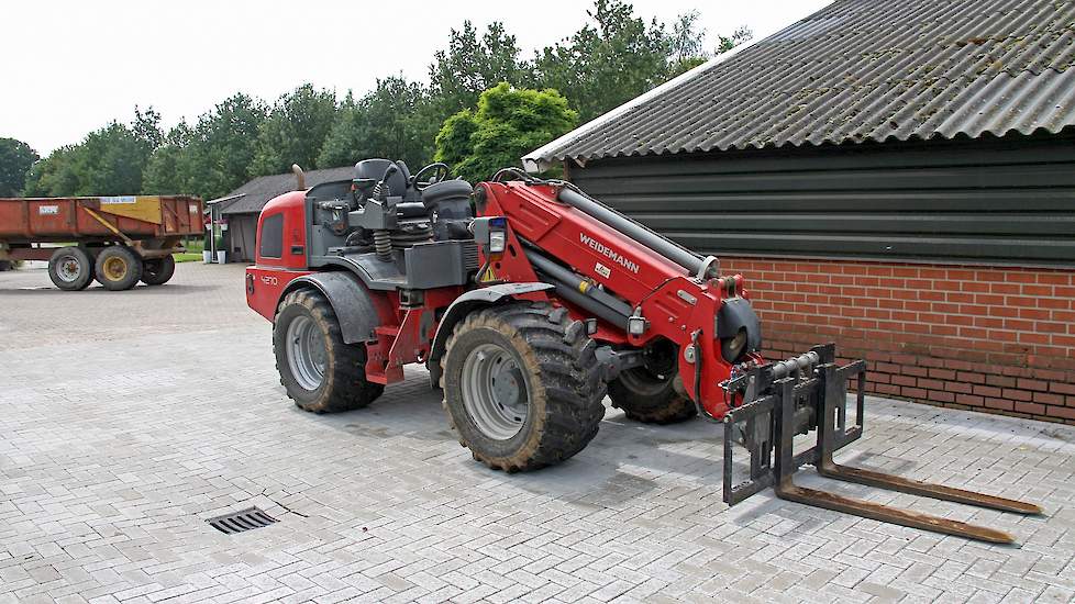 Van Oosterhout heeft een Weidemann telescooplader waarmee hij houtsnippers in de container kan kiepen. Ook laadt hij hier zelf zijn kuikens mee uit en haalt hij zelf de mest uit zijn stallen. „Zelf ben ik zuinig op mijn stallen. Als ik dat uitbesteed weet