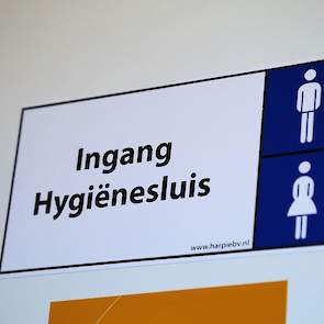 Net voor de poort is de toegang, eveneens met codeslot, tot de hygiënesluis. Bij binnenkomst in de hygiënesluis is er een kleine voorruimte en dan drie doorloopdouches met voldoende opbergruimte voor eigen kleding.