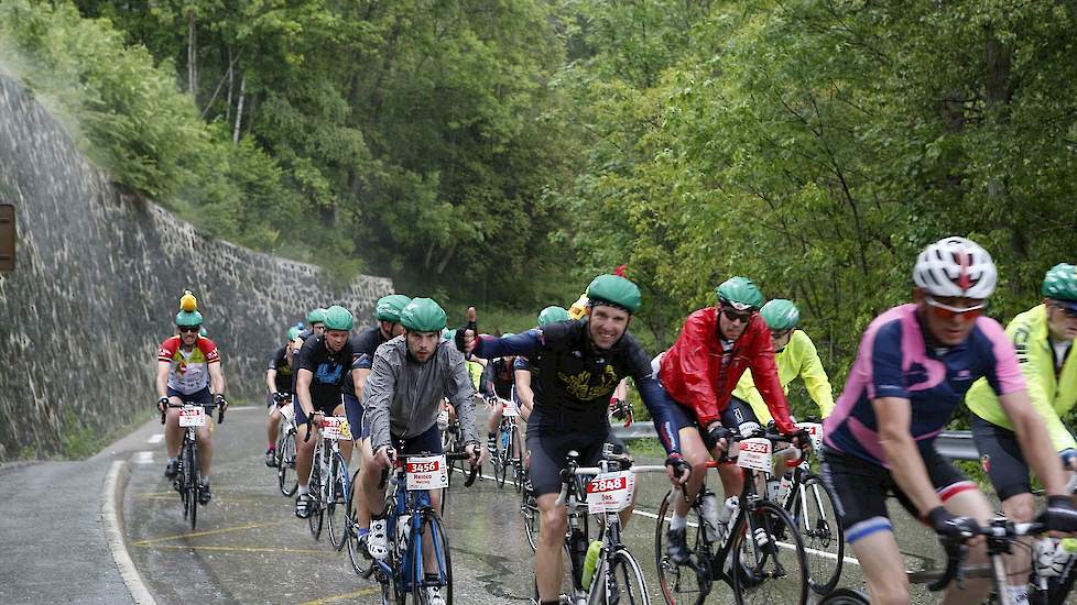 Tijdens de laatste saamhorigheidsklim brak het noodweer los. Met de nodige hermannetjes klimt de groep naar boven. Jos van Leeuwen, vleeskuikenhouder in Helden, in midden met duim omhoog, fietst vrolijk verder. Tot bocht 7 waar ze moeten stoppen. Schuilen