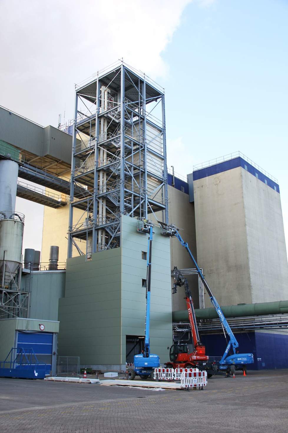 De toren voor de verhittingslijn - hier in aanbouw - is tegen de bestaande fabriek aan gebouwd.